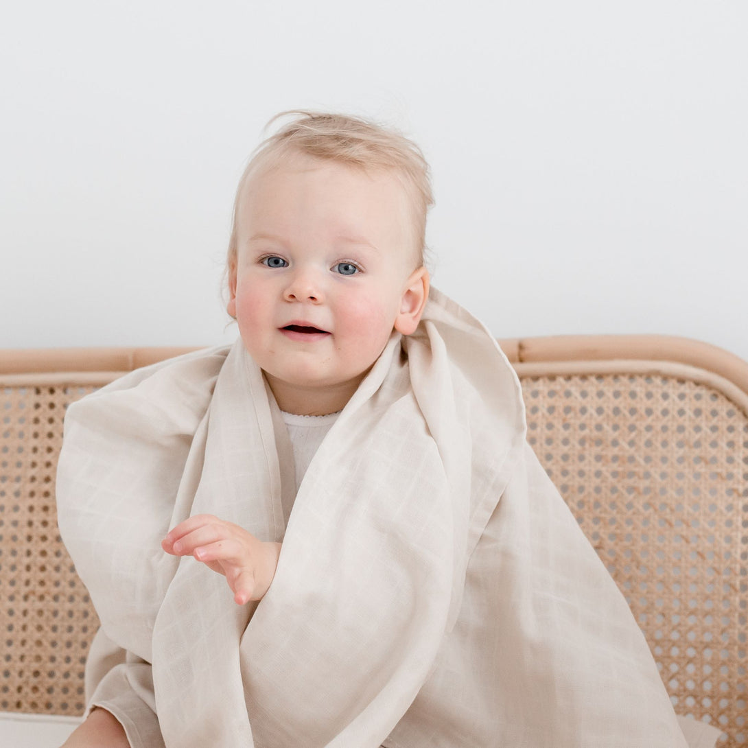 Baby wearing Muslin Swaddle Blanket | Oat (Organic)