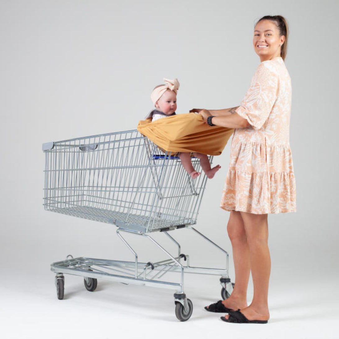 Baby sitting in 5 in 1 mama cover in shopping cart