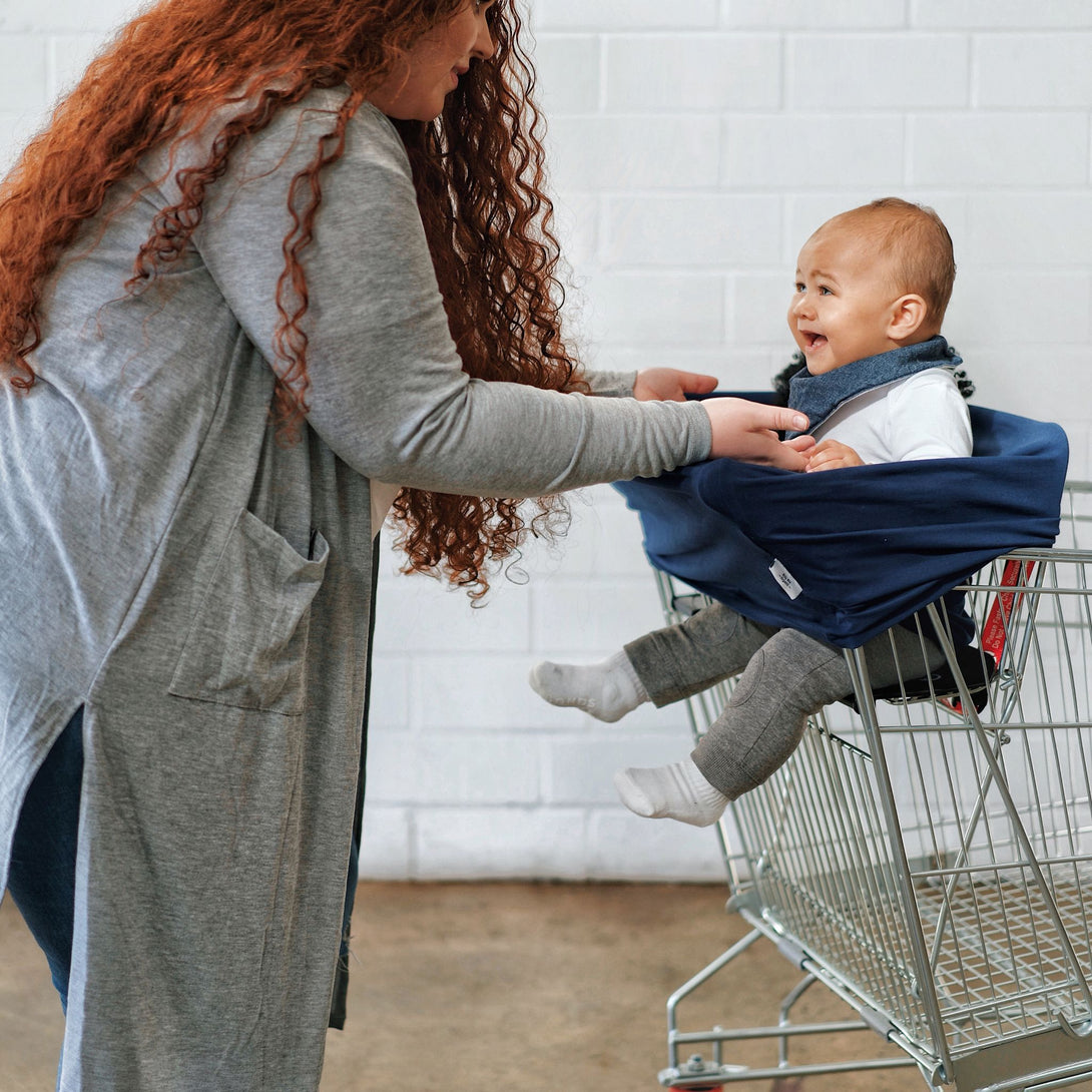 Baby sitting in 5 in 1 mama cover in shopping cart