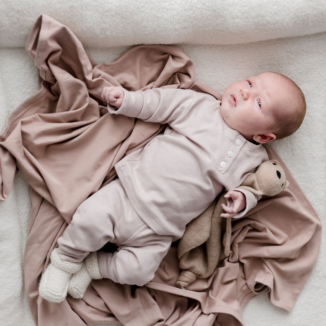 Baby laying on Stretchy Swaddle baby Blanket | Sunset (Organic)