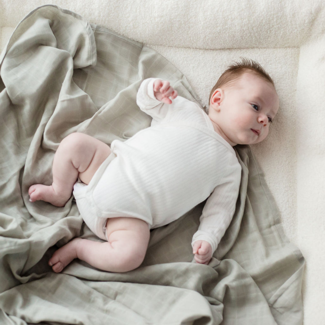 Baby laying on Muslin Swaddle Blanket | Sage Green (Organic)