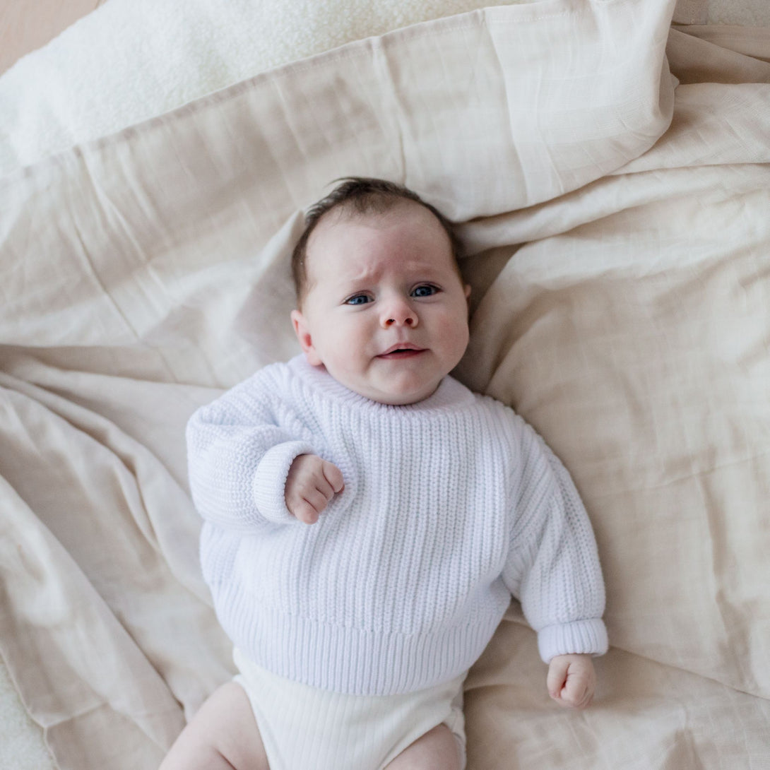 Baby laying on Muslin Swaddle Blanket | Oat (Organic)