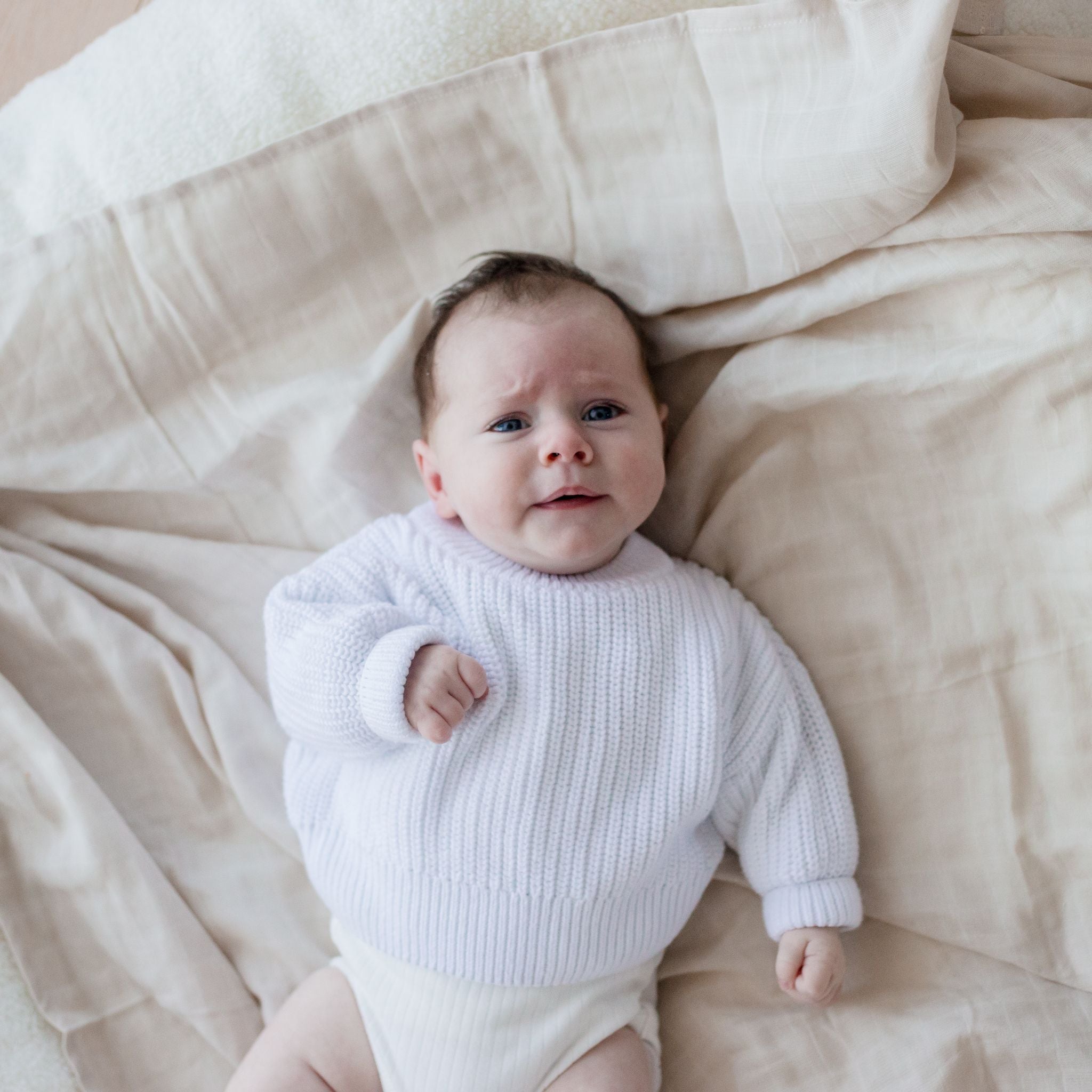 Baby laying on Muslin Swaddle Blanket | Oat (Organic)